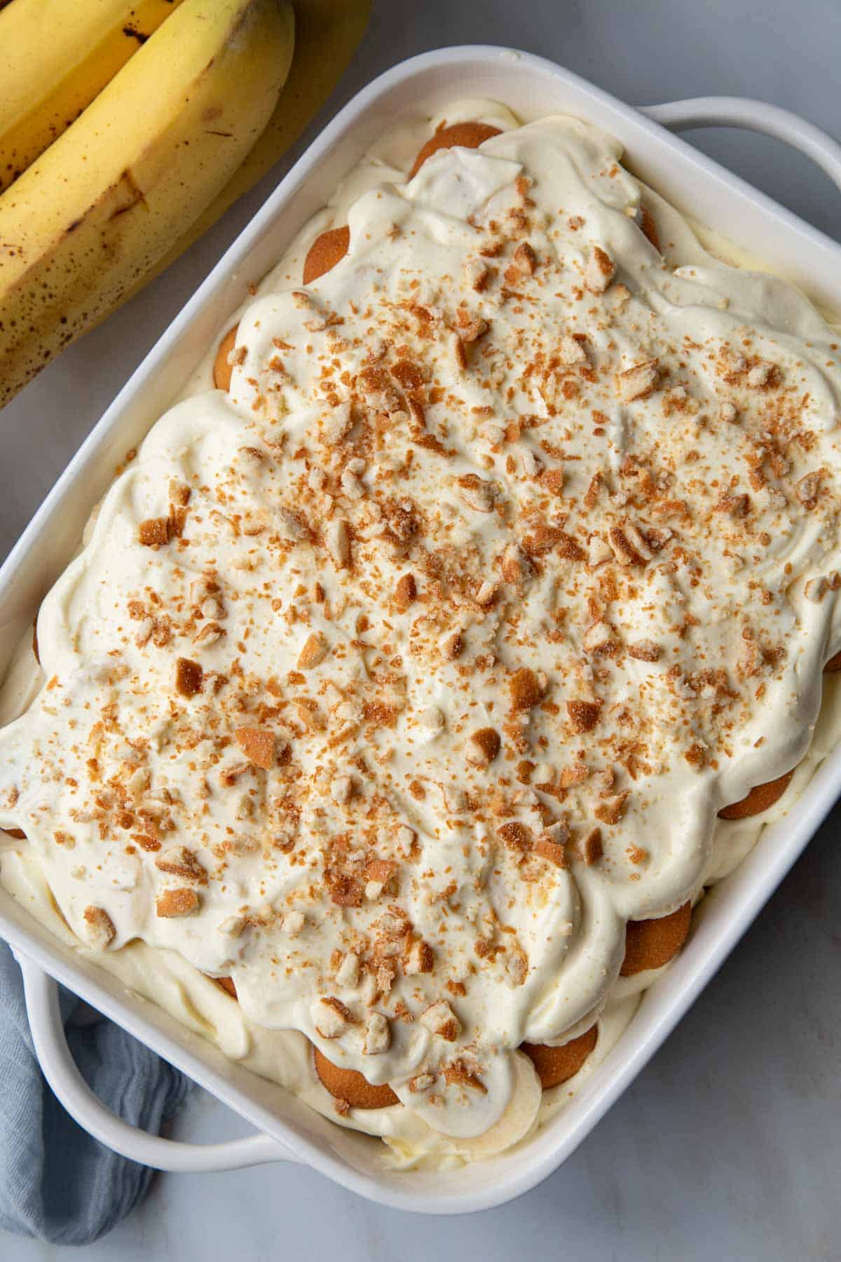 banana pudding in a white baking dish next to bananas.