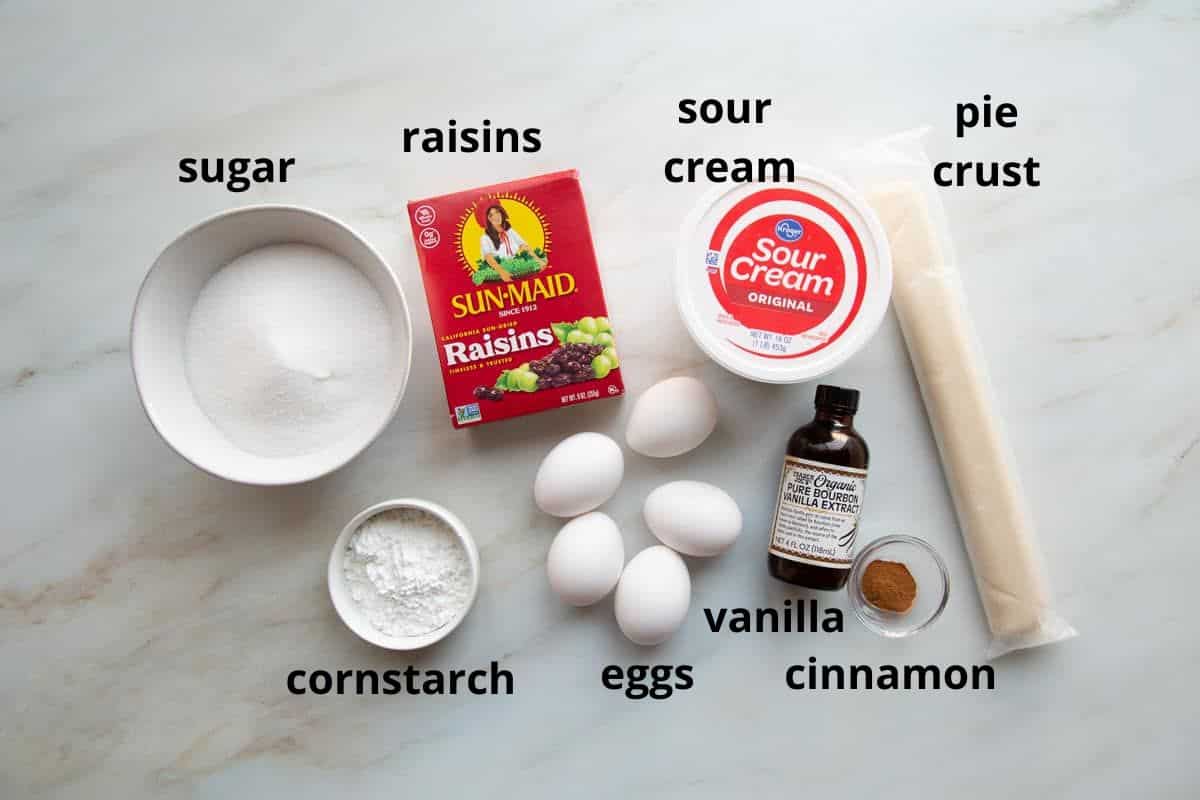 sour cream, pie crust, raisins, and other ingredients on a white surface.
