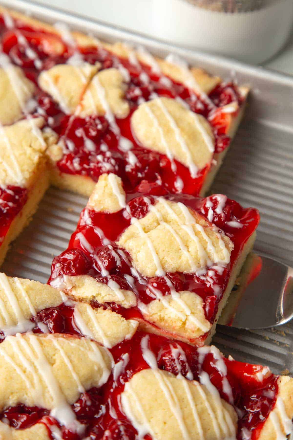 slice of cherry coffee cake in a metal pan.