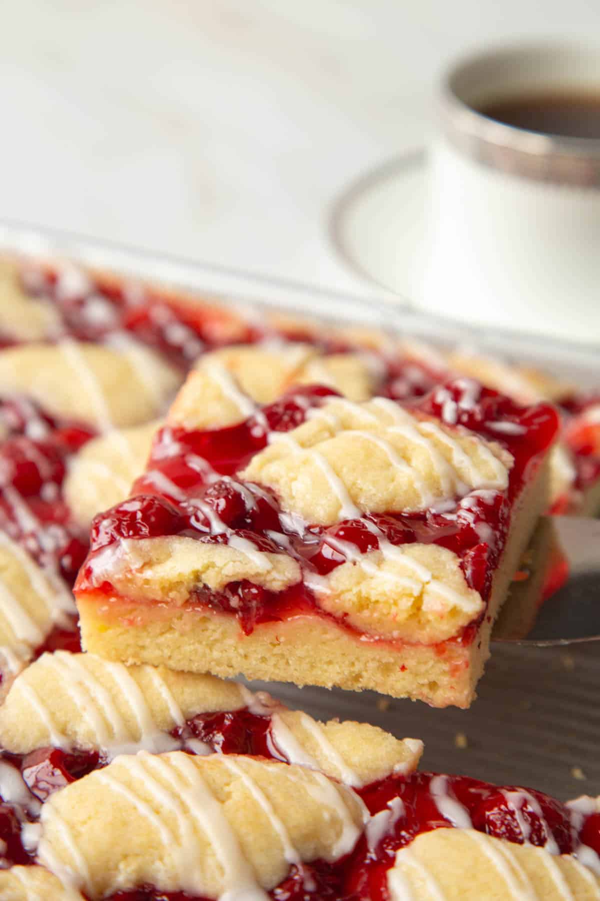 spatula lifting a piece of cherry coffee cake out of a pan.