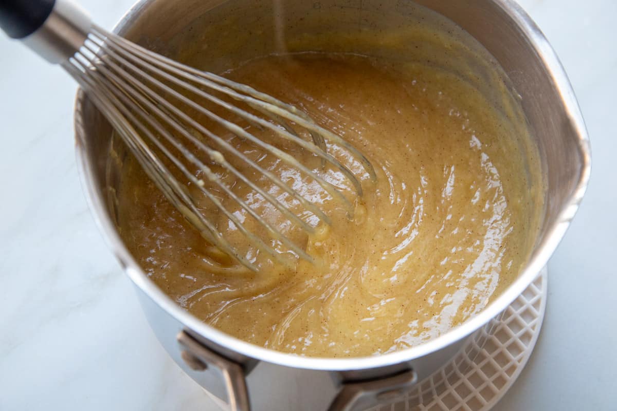 cinnamon flavored pudding mixture in a saucepan with a whisk.