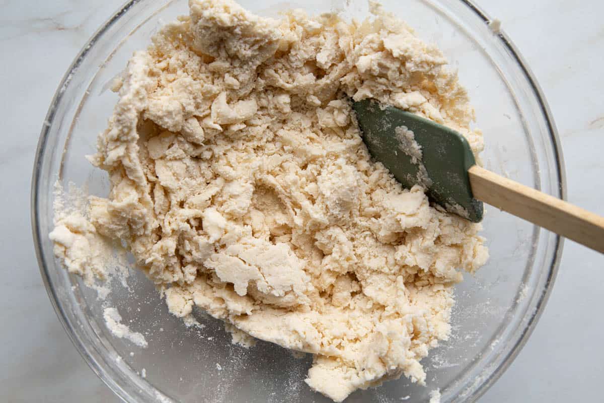 wet, shaggy pie dough in a glass bowl.