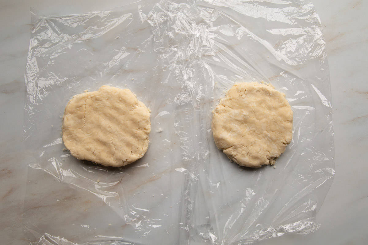 two disks of crisco pie dough on pieces of plastic wrap.