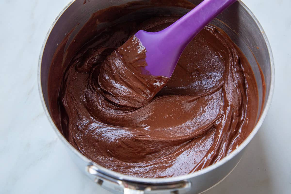 melted chocolate in a saucepan with a purple spatula.