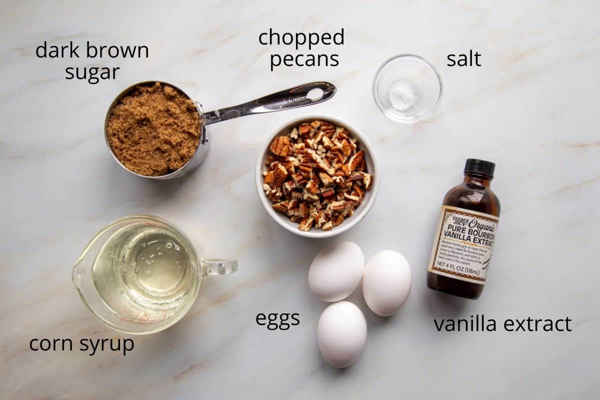 pecans, corn syrup, eggs, and other ingredients on a white countertop.