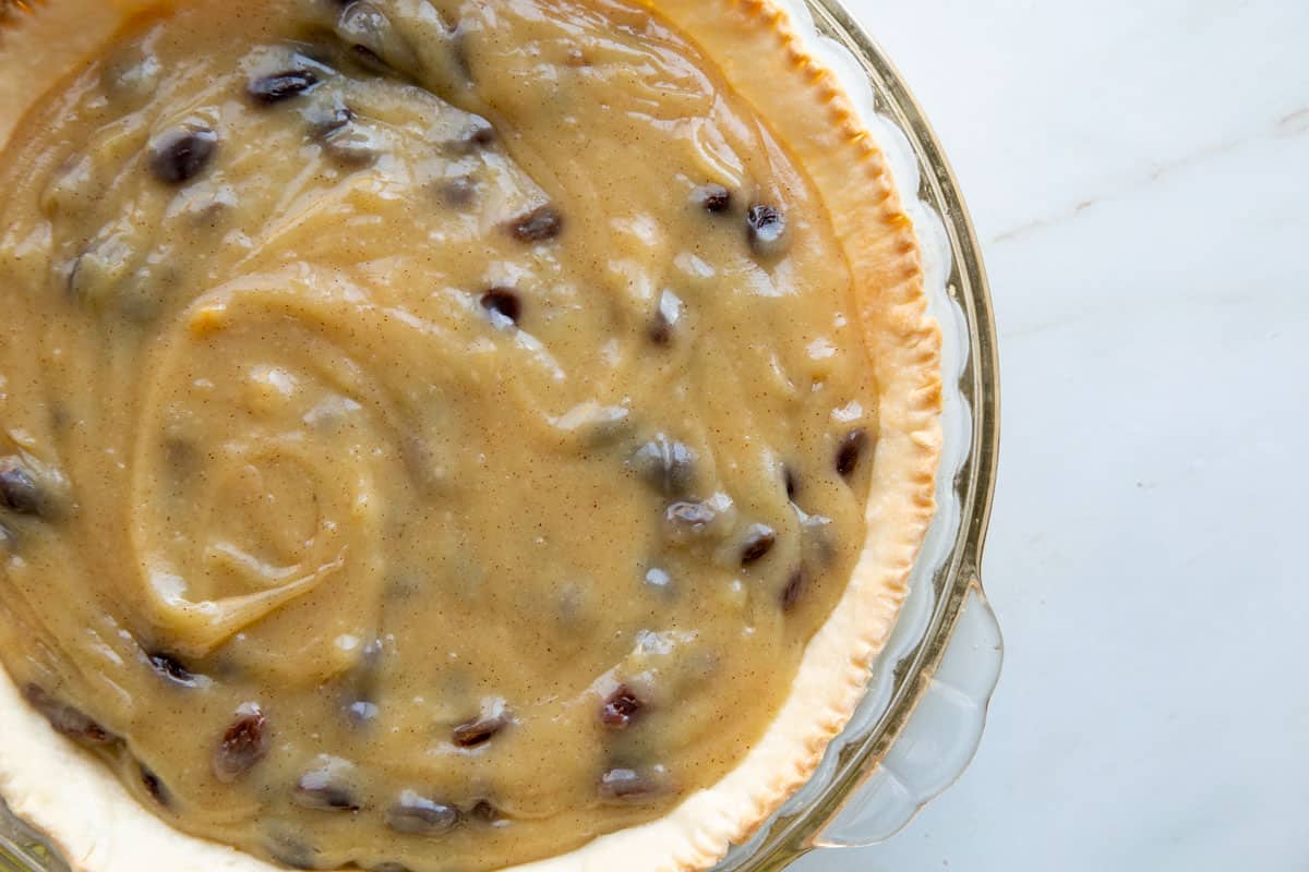 cinnamon raisin pudding filling in a baked crust and clear pie pan.