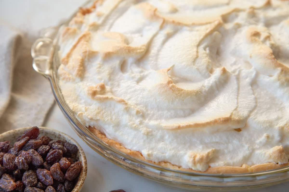 toasted meringue-topped pie next to a small bowl of raisins.