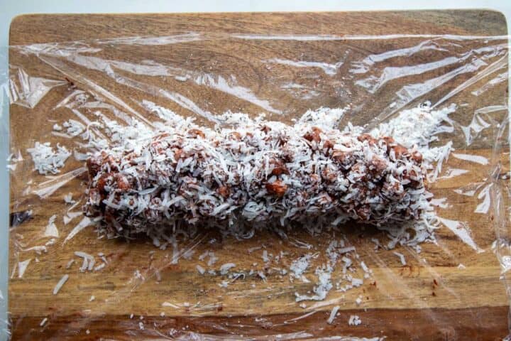 cookie log rolled in coconut on a piece of plastic.