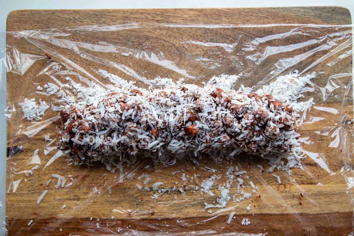 cookie log rolled in coconut on a piece of plastic.