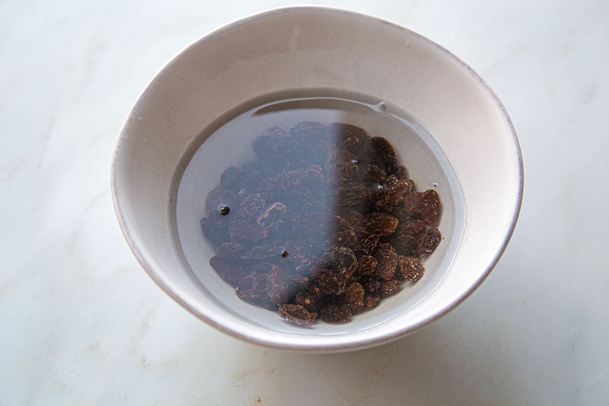 raisins soaking in water in a small white bowl.