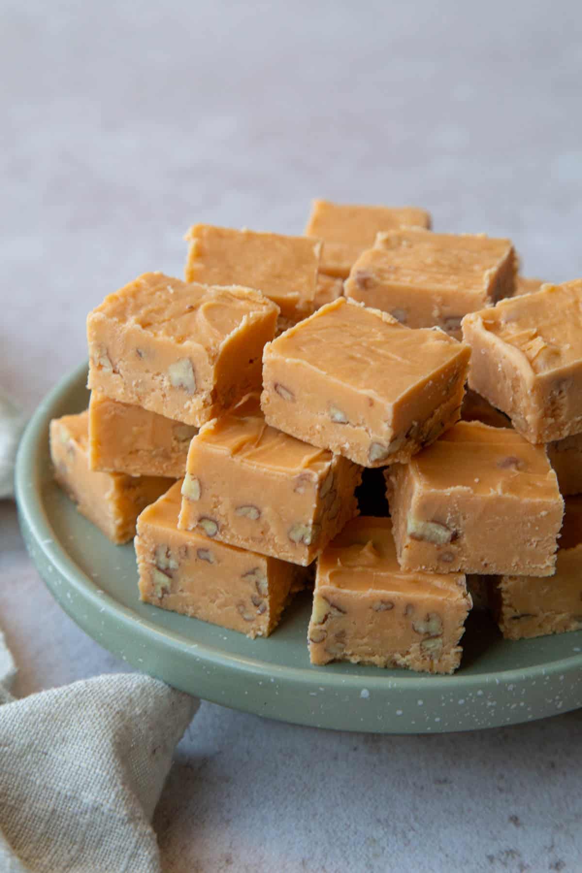 green platter topped with pieces of butterscotch fudge with pecans.