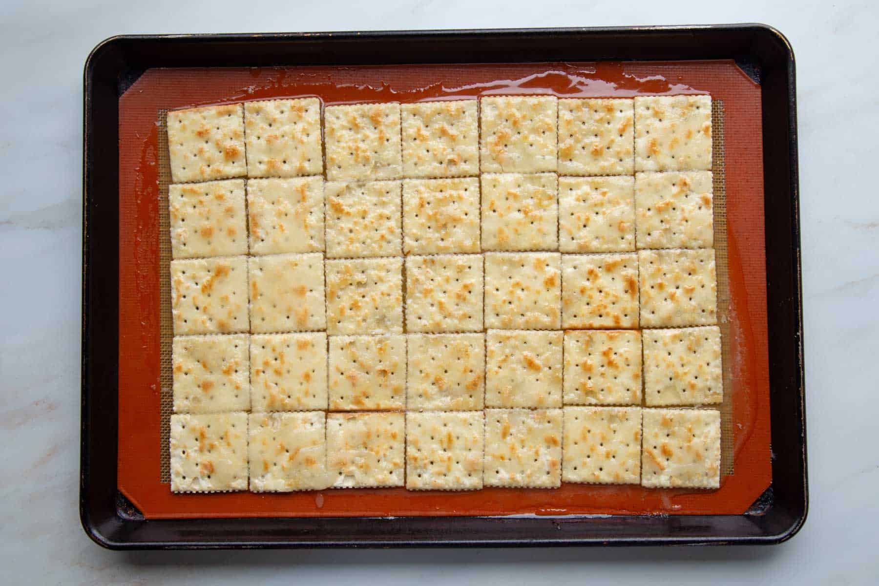 saltine crackers covered with sugar and butter mixture on a silicone lined baking sheet.