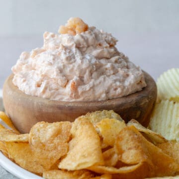 a large bowl of shrimp dip next to chips.