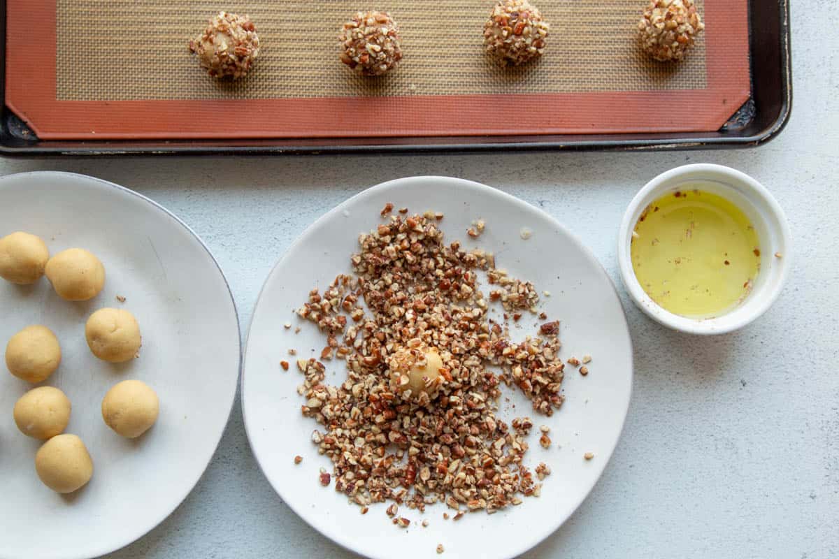 cookie dough ball being rolled in pecans.