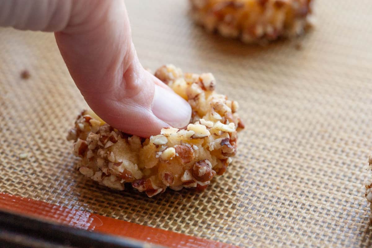 thumb making an indentation on a thumbprint cookie.