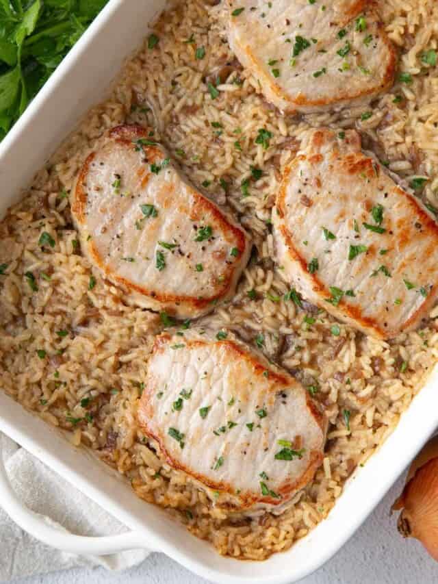 pork chops and rice casserole in a white dish, topped with parsley.