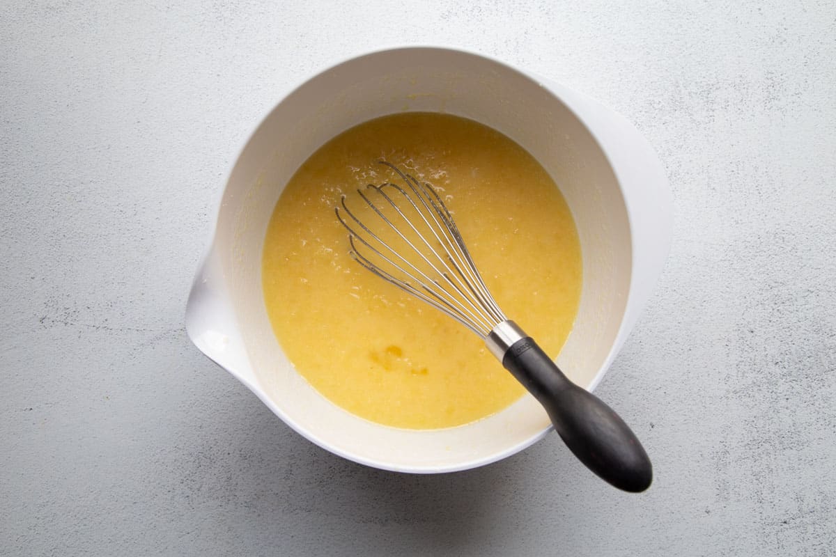 egg and butter mixture in a white bowl with a whisk.