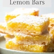 lemon bars stacked on a green cake plate.