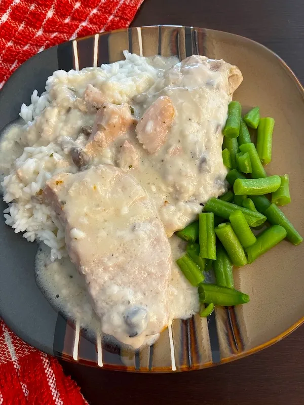 2 pork chops in sauce over rice and green beans.