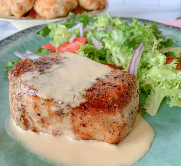 a seared pork chop with au jus sauce and a salad.