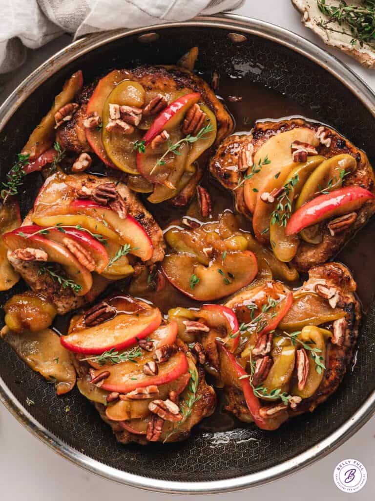 pork chops with applies in a frying pan.