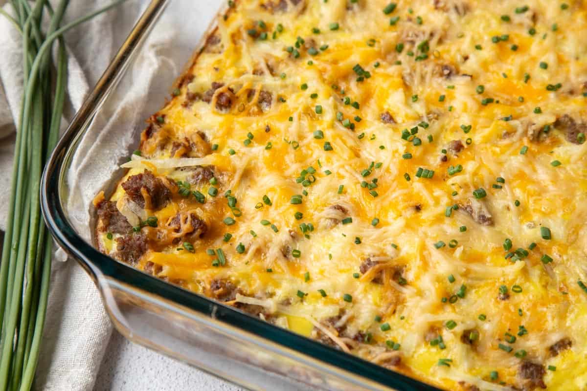 breakfast pizza with sausage and cheese in a glass casserole dish.