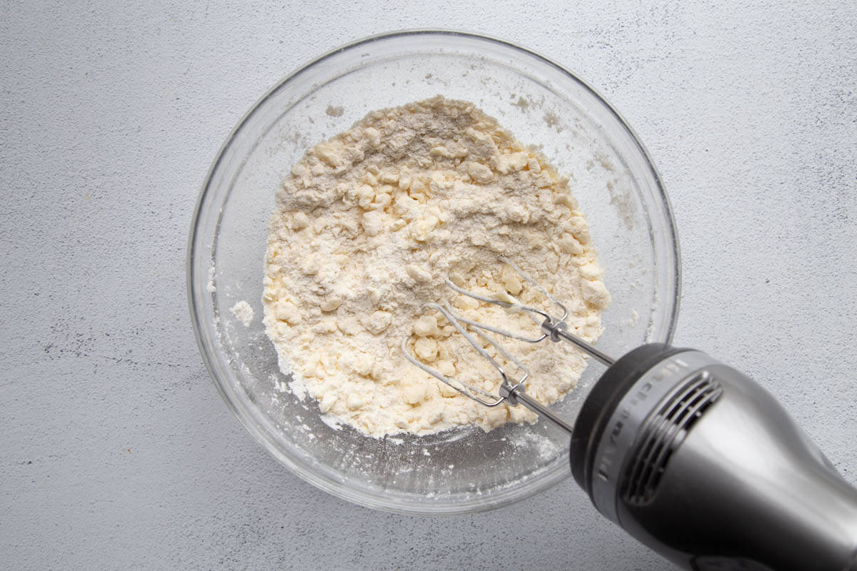 flour and butter mixture in a glass bowl with a hand mixer.