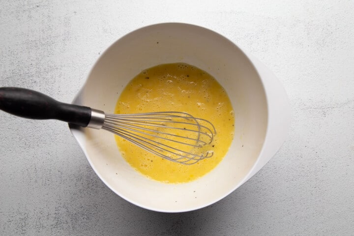 egg and milk mixture in a bowl with a whisk.