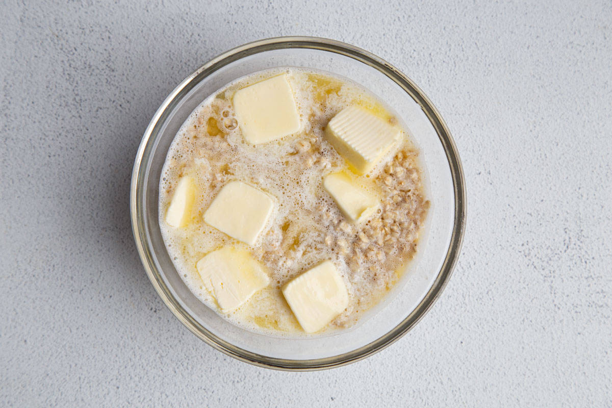 oats and water in a glass bowl with pats of butter.