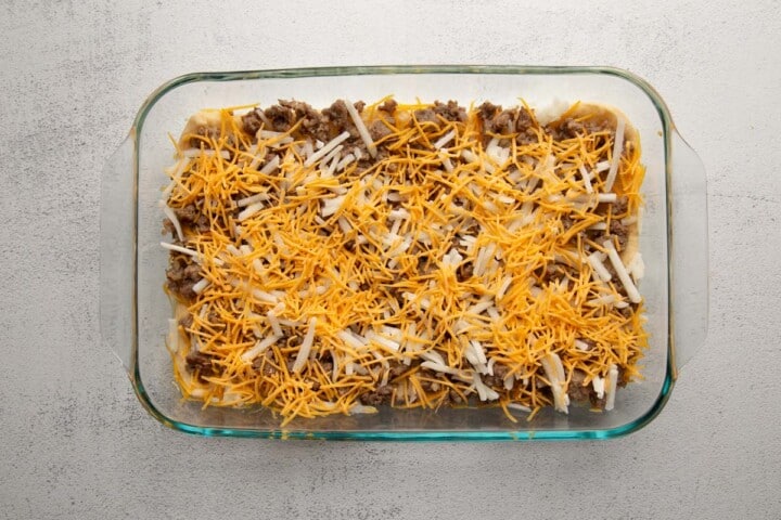 sausage, hash browns, and cheese in a glass dish.