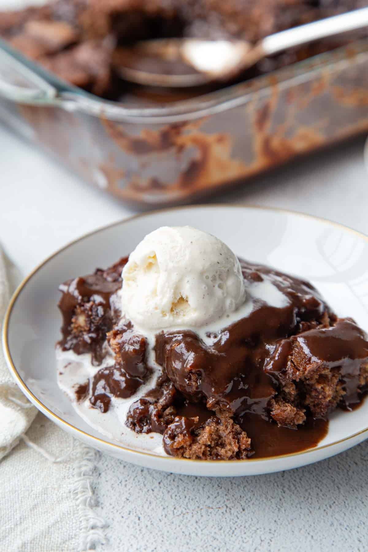 chocolate pudding cake topped with ice cream in a dish.