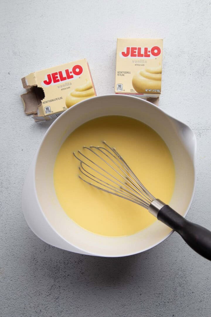 vanilla pudding in a white bowl with a whisk.