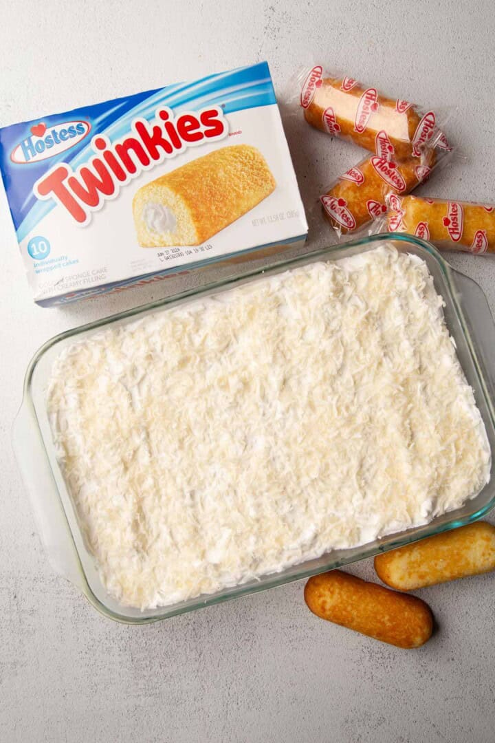 twinkie cake topped with coconut next to a box of Twinkies.