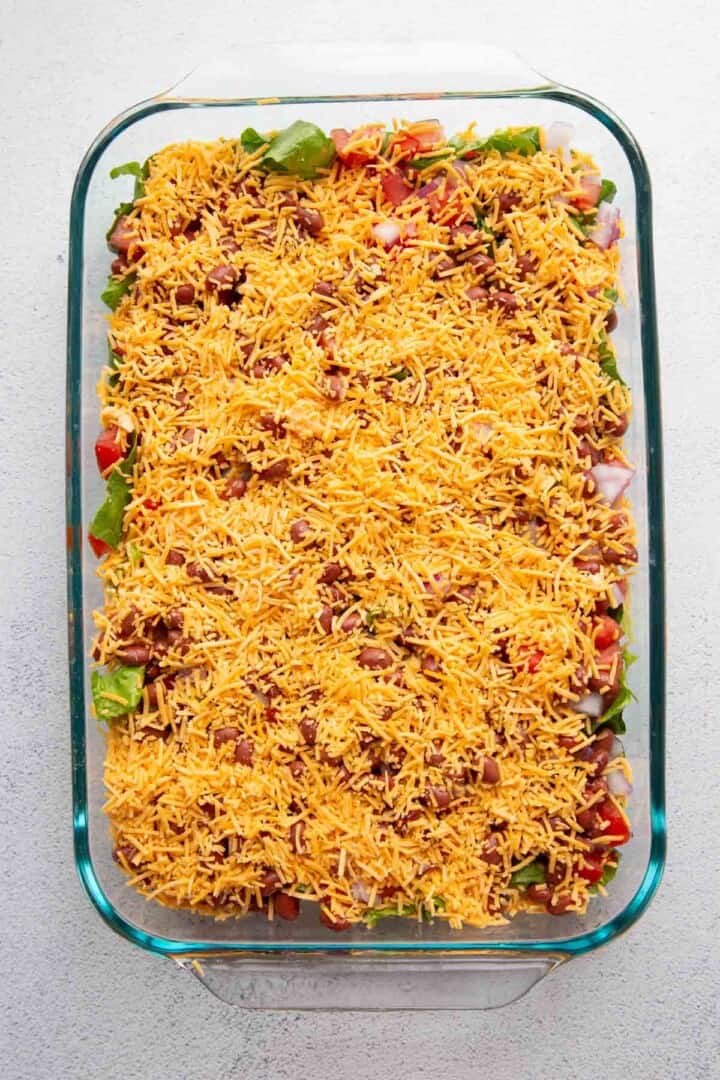 cheese and beans on top of tomatoes, red onion, and lettuce.