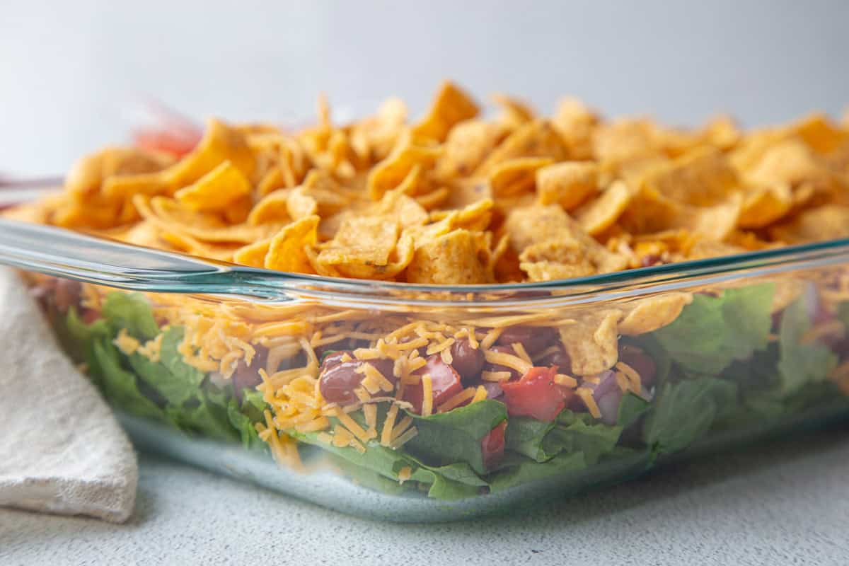 fritos on top of a taco salad in a glass dish.