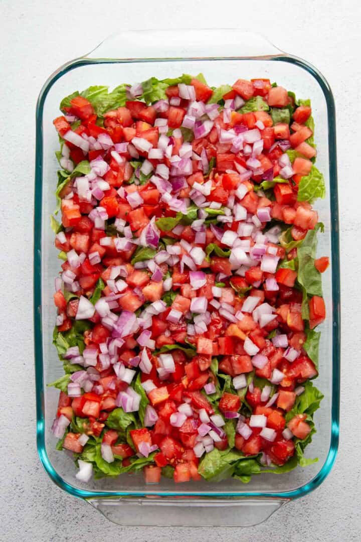 red onion and tomatoes on top of lettuce.