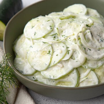 cucumbers in sour cream in a low green bowl.