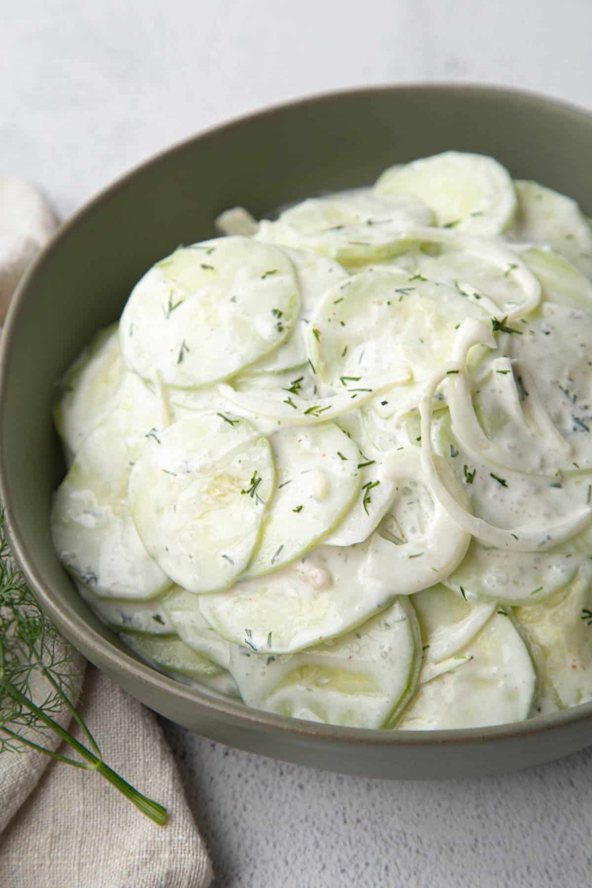 sour cream cucumbers in a low green bowl.