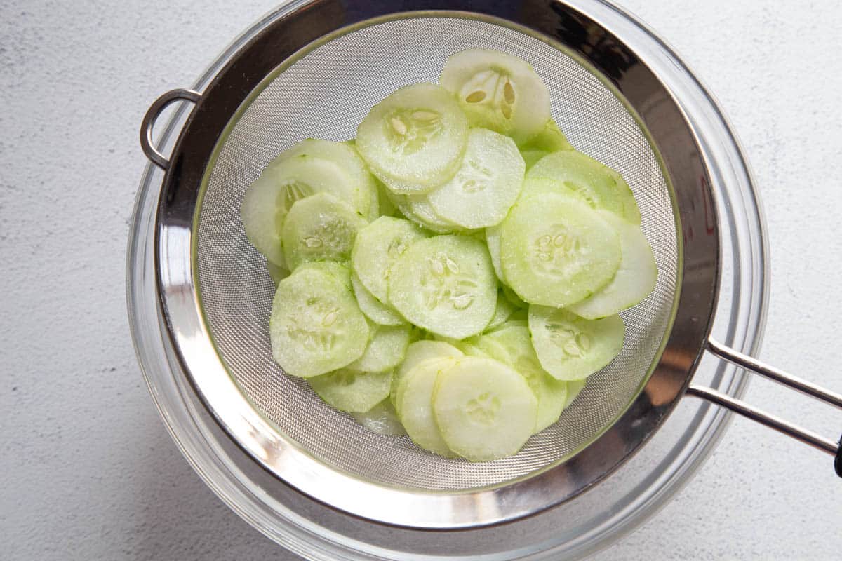 sliced cucumbers in a colander.