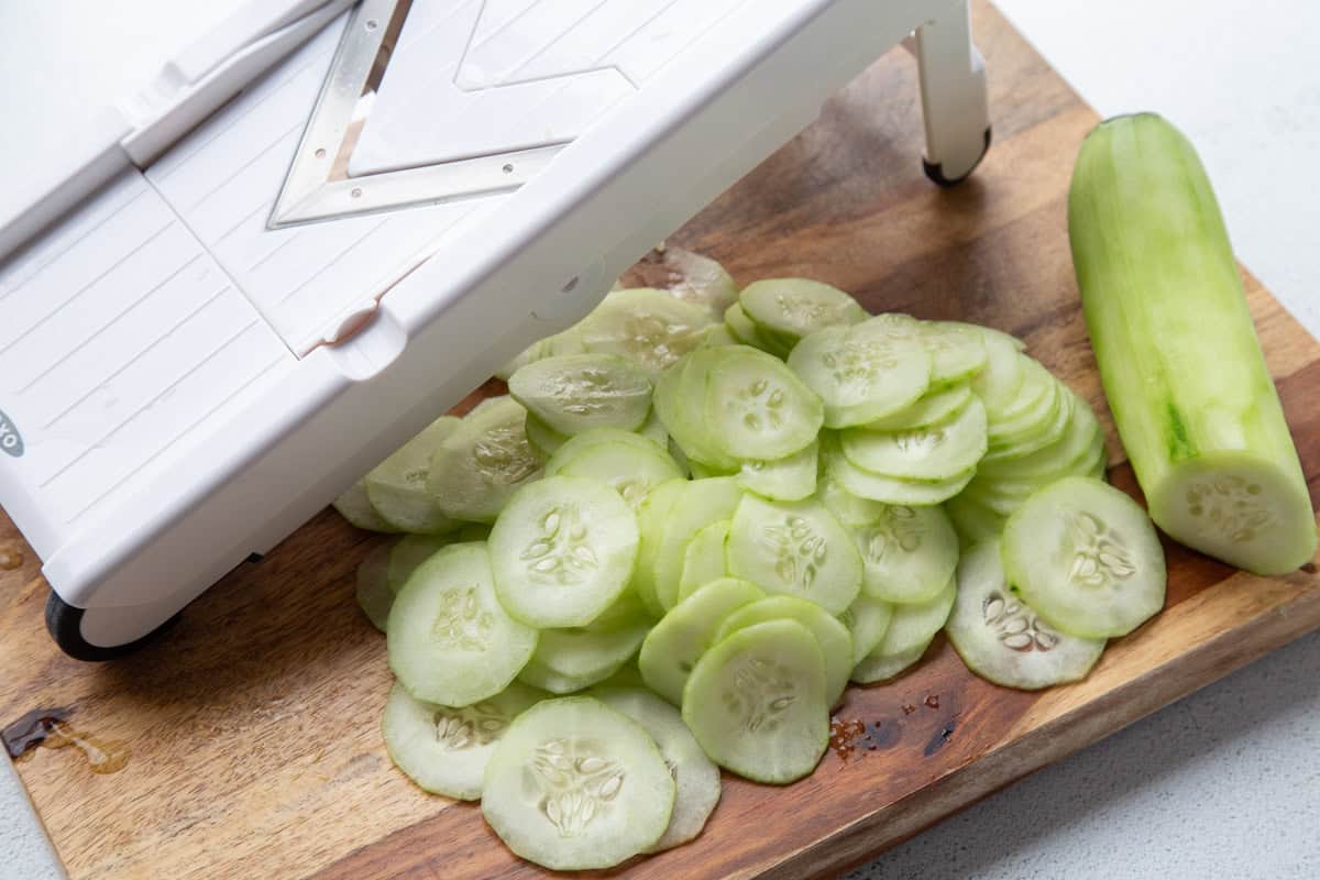 thinly sliced cucumbers next to mandoline.