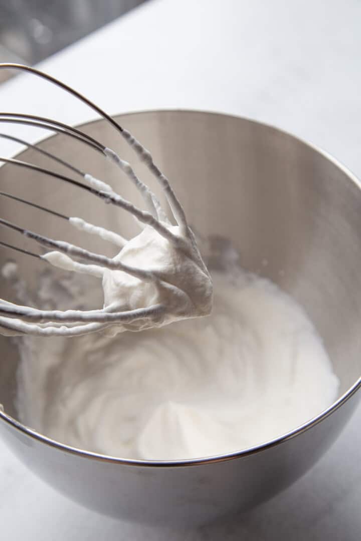 whipped cream in a metal bowl with a beater.