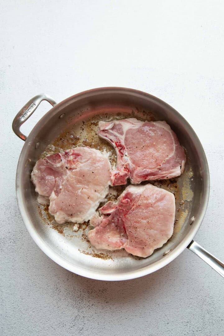 raw pork chops in a skillet.