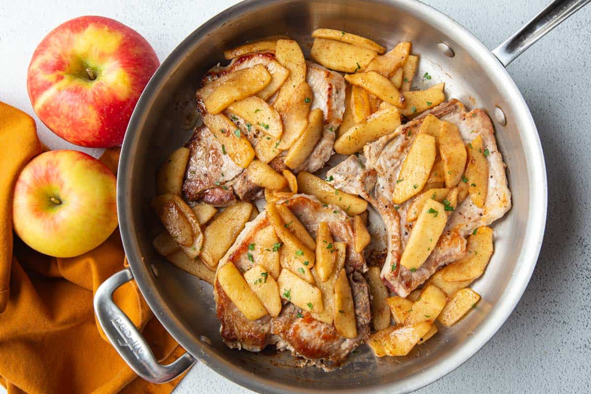 skillet filled with pork chops and apples.