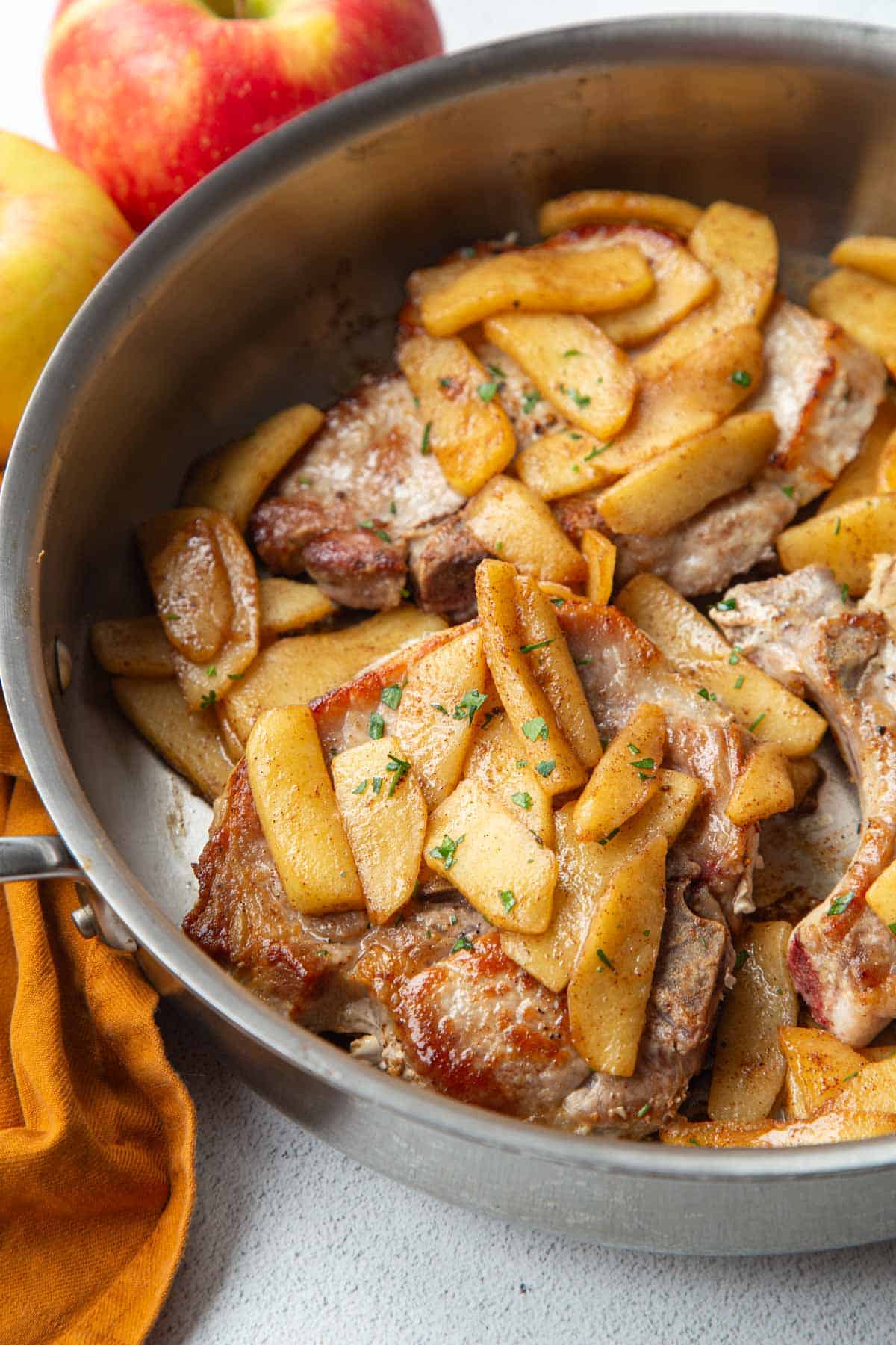 pork chops and apples in a metal skillet.