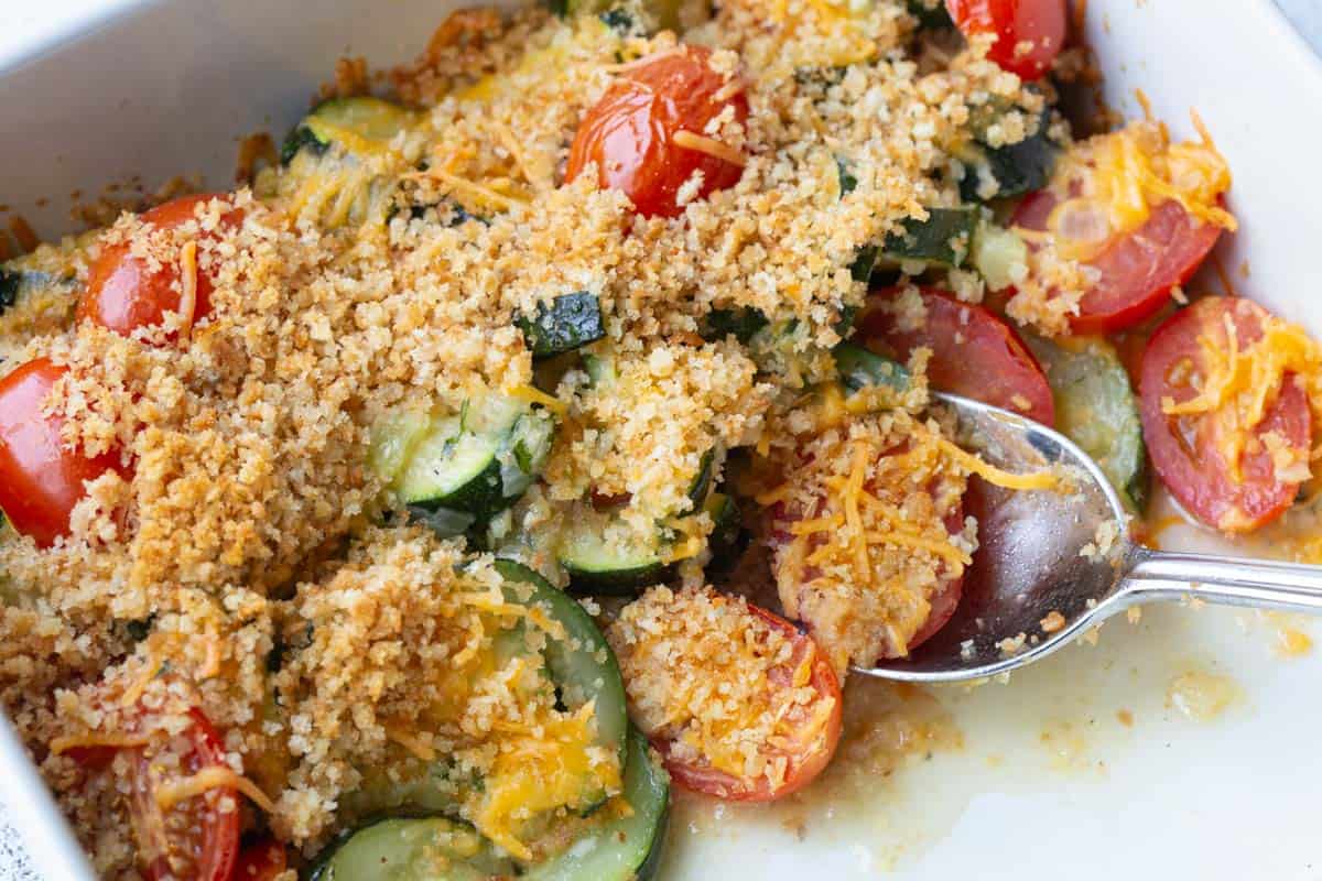 casserole dish filled with zucchini and tomatoes topped with breadcrumbs.