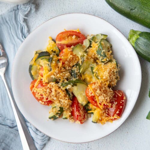 zucchini tomato casserole serving on a white plate.
