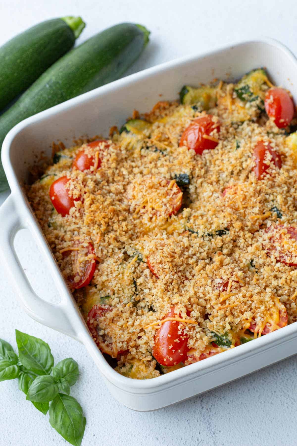whole zucchini tomato casserole in a white dish.