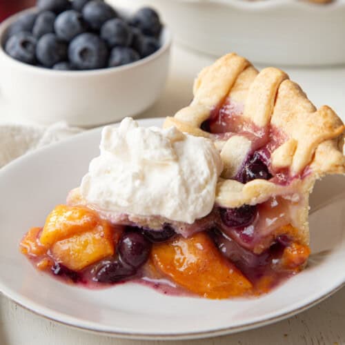 slice of peach blueberry pie on a white plate.