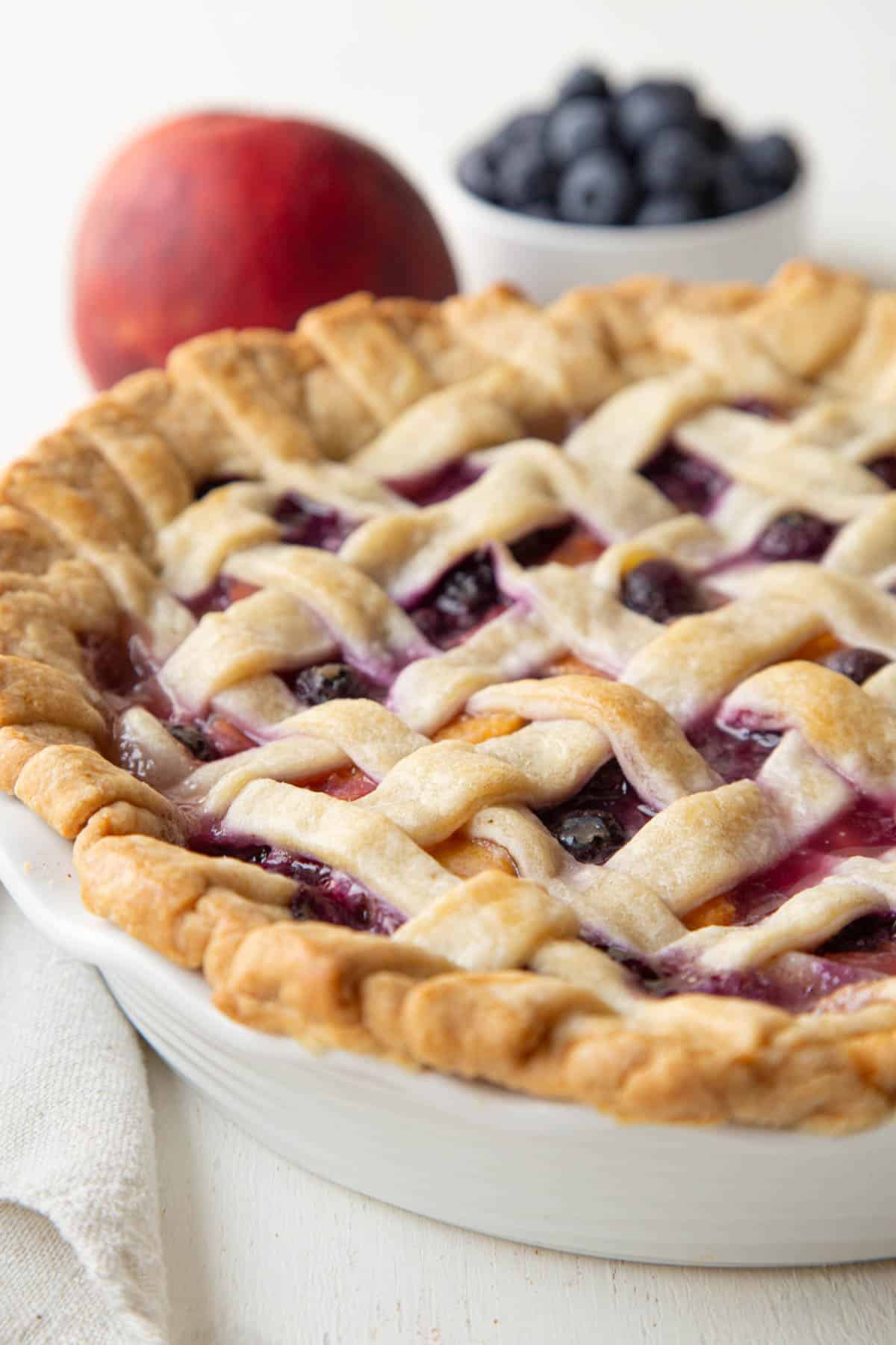 whole peach blueberry pie with lattice crust.