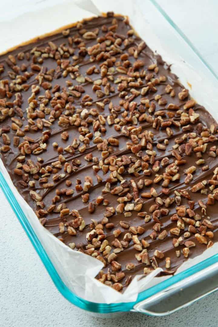chocolate and pecans on top of a cookie base in a pan.